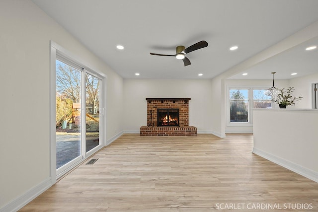 unfurnished living room featuring light wood-type flooring, a fireplace, baseboards, and recessed lighting