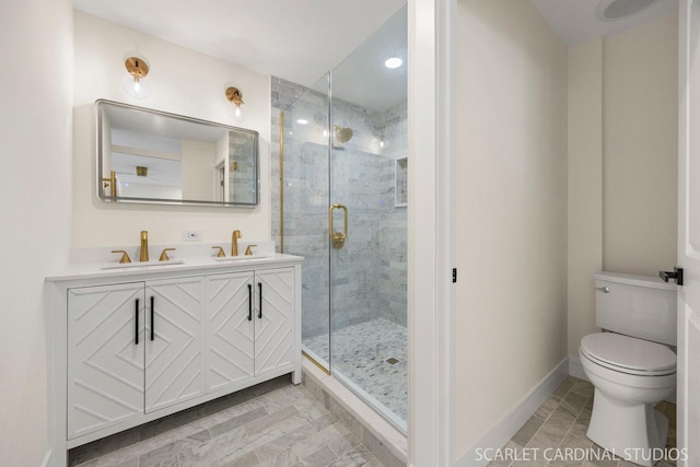 full bathroom with double vanity, toilet, a sink, a shower stall, and baseboards