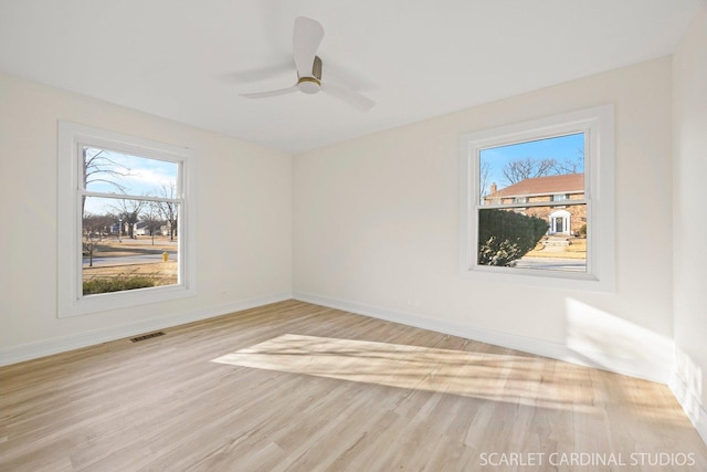 unfurnished room featuring ceiling fan, visible vents, light wood-style flooring, and baseboards