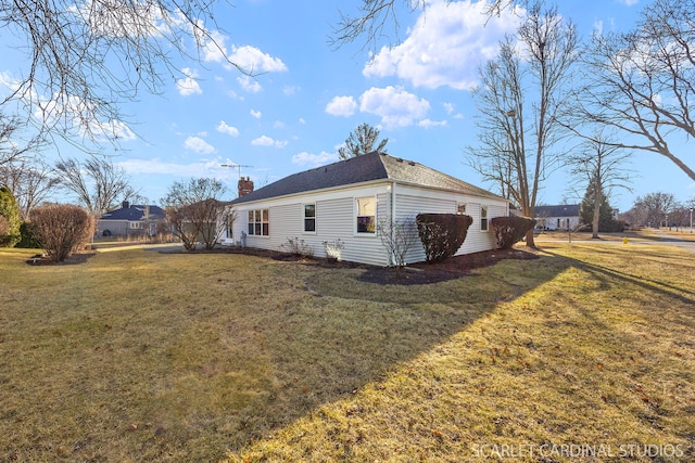 view of side of property with a chimney and a lawn