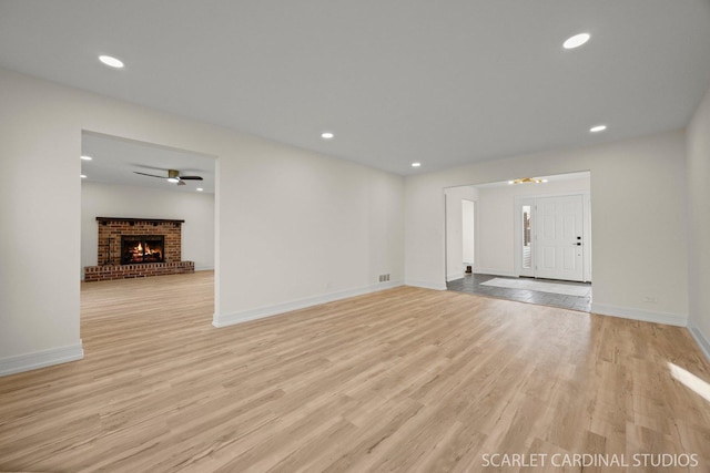 unfurnished living room featuring light wood finished floors, a fireplace, and recessed lighting