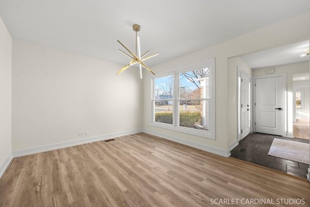 unfurnished dining area with a chandelier, visible vents, baseboards, and wood finished floors