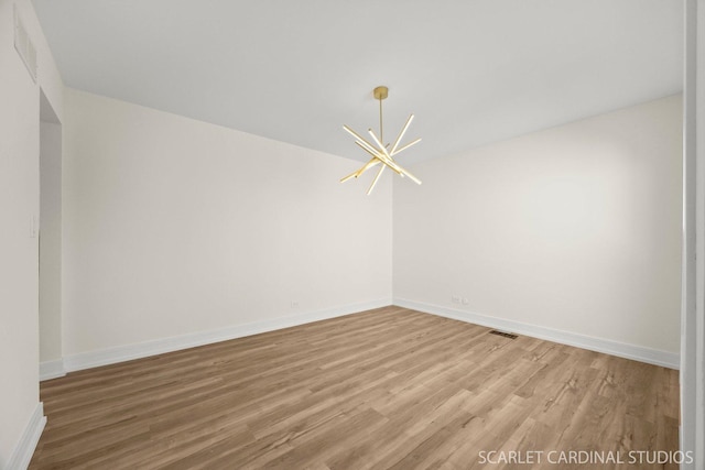 empty room with baseboards, visible vents, light wood-style flooring, and a notable chandelier