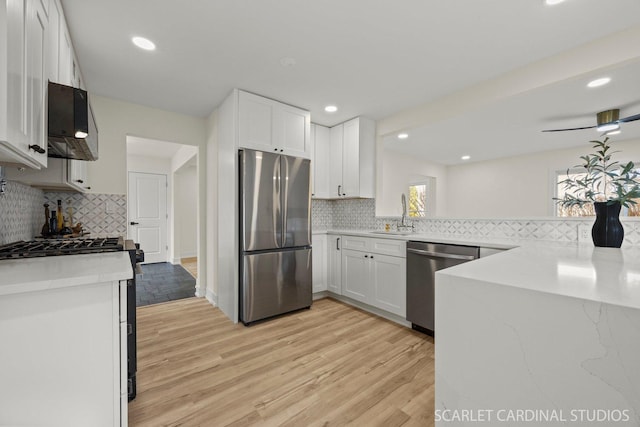 kitchen featuring white cabinetry, light wood-style flooring, appliances with stainless steel finishes, and extractor fan