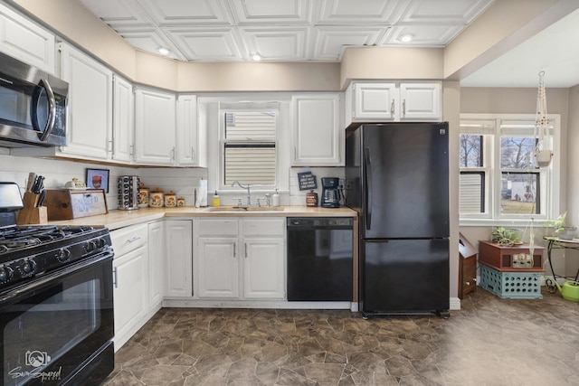 kitchen featuring a sink, white cabinetry, light countertops, black appliances, and an ornate ceiling