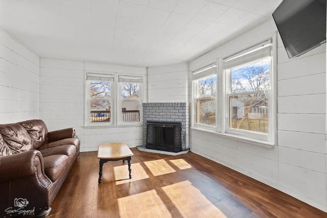 living room featuring a fireplace, wood walls, and wood finished floors