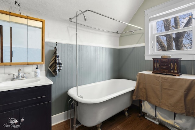 full bath featuring vaulted ceiling, a freestanding bath, vanity, and wood finished floors