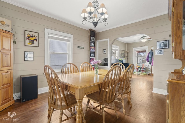 dining room featuring arched walkways, ornamental molding, dark wood-style flooring, and baseboards