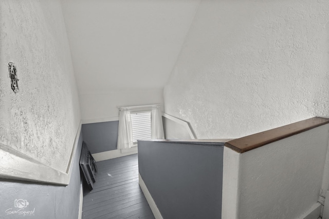 stairway featuring vaulted ceiling, a textured wall, and hardwood / wood-style floors