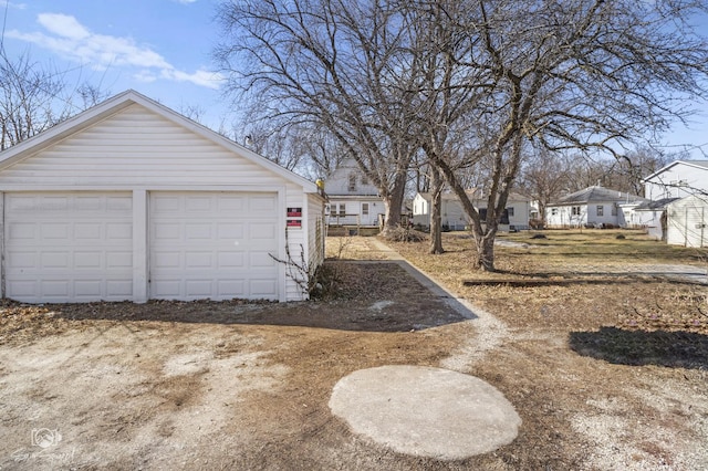 view of yard featuring a residential view, a detached garage, and an outdoor structure