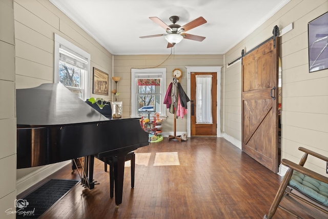 interior space featuring ornamental molding, a barn door, wood finished floors, and a ceiling fan