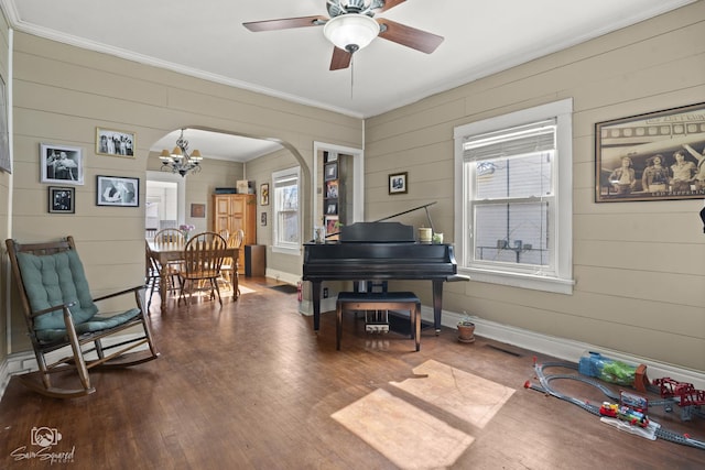 sitting room featuring arched walkways, ornamental molding, wood finished floors, and baseboards