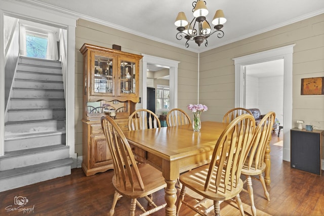 dining room with a healthy amount of sunlight, a notable chandelier, stairs, and dark wood-type flooring