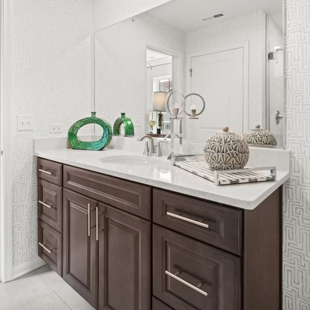 bathroom featuring tile patterned flooring, visible vents, vanity, a tile shower, and wallpapered walls