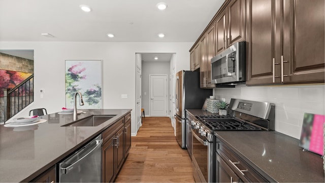 kitchen featuring stainless steel appliances, recessed lighting, light wood-style flooring, decorative backsplash, and a sink