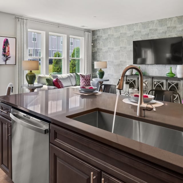 kitchen with a sink, dark countertops, dark brown cabinets, and stainless steel dishwasher