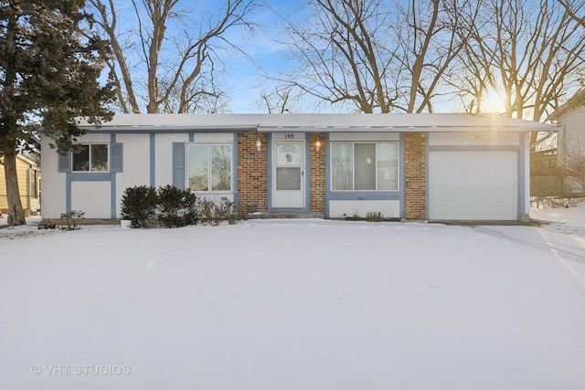 ranch-style home with a garage, brick siding, and stucco siding