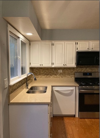 kitchen with gas stove, white cabinetry, a sink, black microwave, and dishwasher