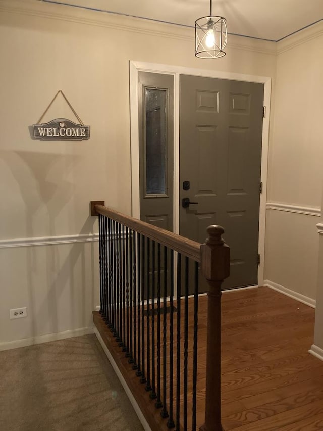 stairway featuring crown molding, wood finished floors, and baseboards