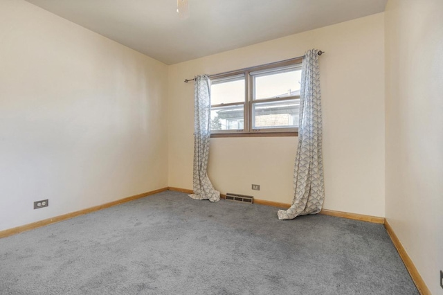 spare room featuring carpet, visible vents, and baseboards