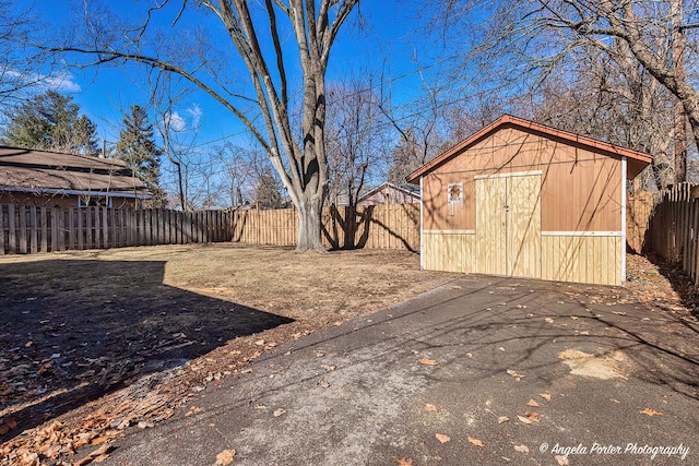 view of yard with a fenced backyard, a storage unit, and an outbuilding