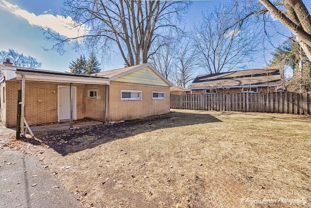 view of home's exterior featuring a yard, fence, and brick siding