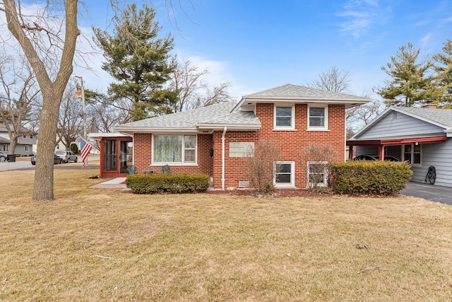 tri-level home featuring a shingled roof, a front yard, and brick siding