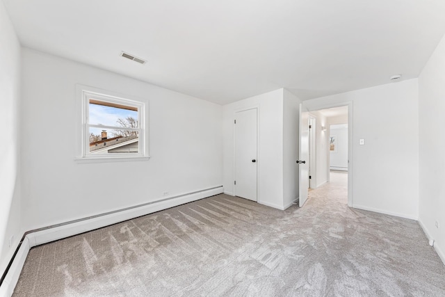 unfurnished bedroom featuring a baseboard heating unit, baseboards, visible vents, and carpet flooring