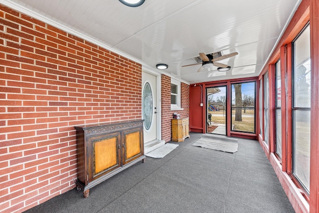 unfurnished sunroom with ceiling fan