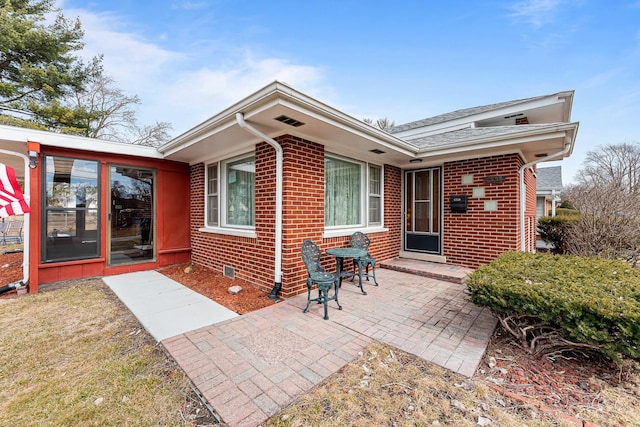 rear view of property featuring a patio area and brick siding