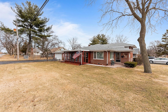 ranch-style house with brick siding, fence, driveway, roof with shingles, and a front lawn