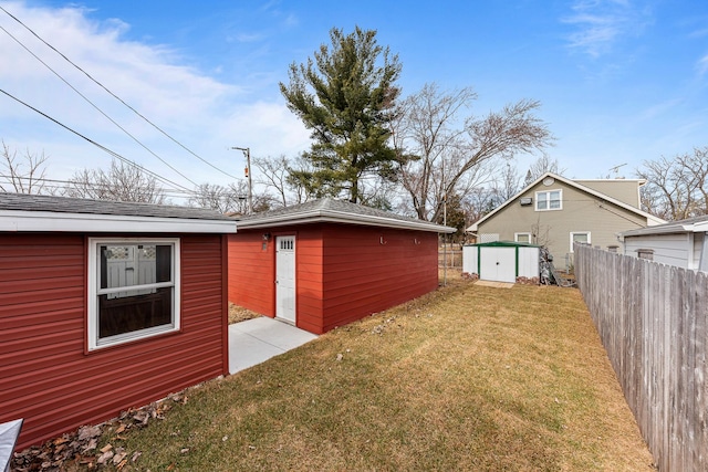 view of side of home with an outbuilding, a yard, and fence