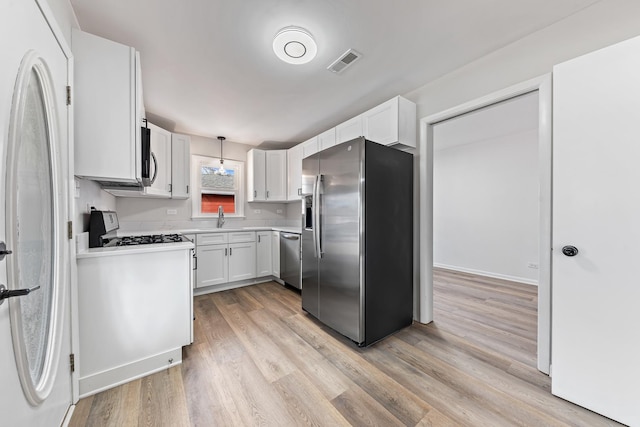 kitchen featuring light wood-style flooring, a sink, visible vents, light countertops, and appliances with stainless steel finishes