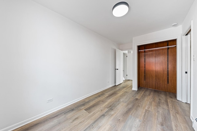 unfurnished bedroom with a closet, baseboards, and wood finished floors