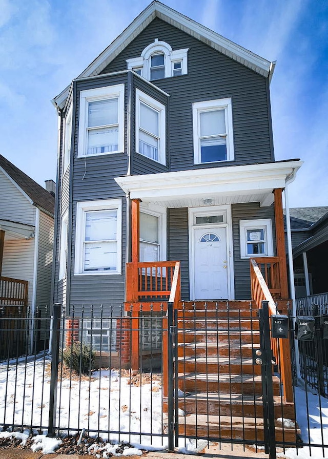 view of front facade with a porch, a fenced front yard, and a gate