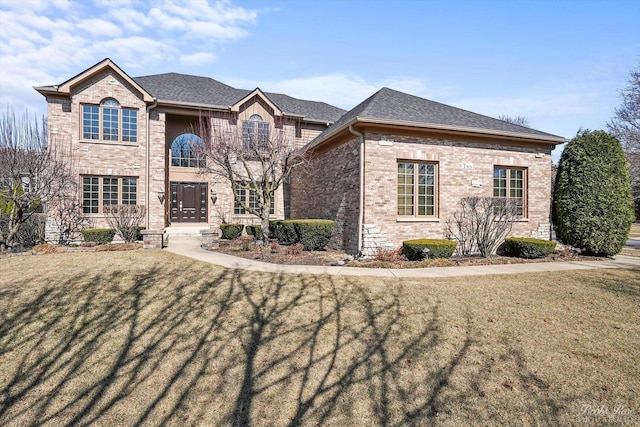 view of front of property with brick siding, a front yard, and a shingled roof