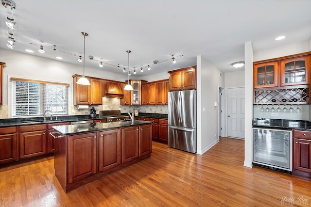 kitchen with premium range hood, beverage cooler, freestanding refrigerator, wood finished floors, and a sink