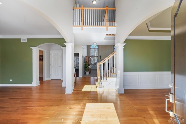 entryway featuring decorative columns, visible vents, wood finished floors, and crown molding