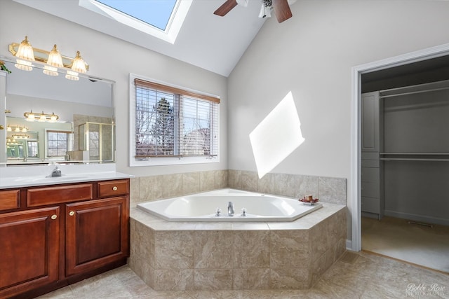 bathroom featuring a shower stall, ceiling fan, a garden tub, vaulted ceiling with skylight, and vanity