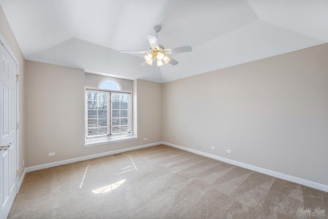 empty room with baseboards, light carpet, a ceiling fan, and vaulted ceiling