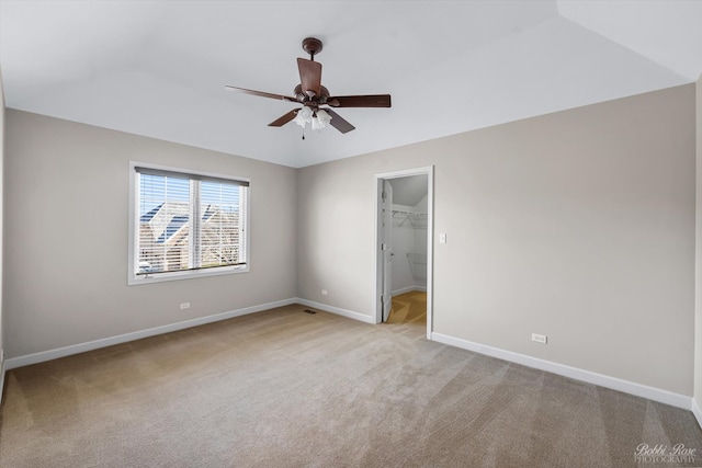 unfurnished bedroom featuring a ceiling fan, baseboards, a spacious closet, a closet, and light carpet