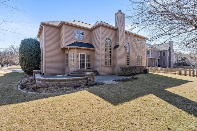 rear view of property featuring a patio area, a chimney, a yard, and fence