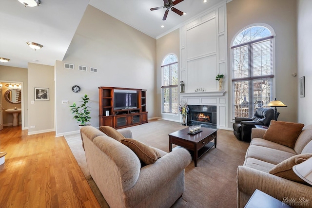 living area with a high ceiling, a ceiling fan, baseboards, and a healthy amount of sunlight