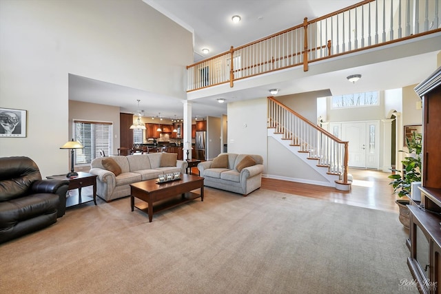 living room with baseboards, a high ceiling, stairs, and light wood finished floors