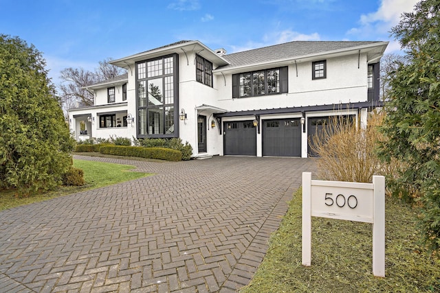 view of front of house with decorative driveway, a garage, and stucco siding