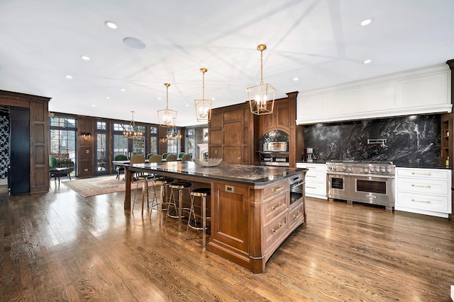 kitchen featuring a spacious island, stainless steel appliances, a breakfast bar area, decorative backsplash, and dark wood-style flooring