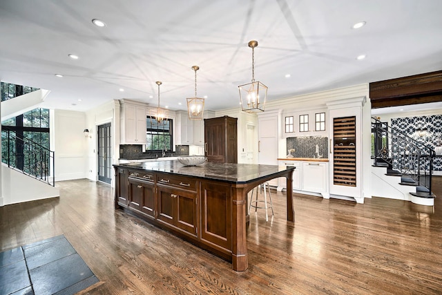 kitchen featuring tasteful backsplash, dark brown cabinets, a kitchen island, a breakfast bar, and dark wood-style floors