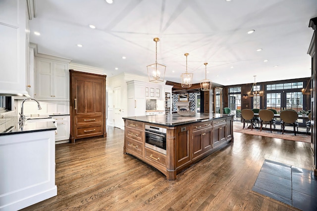 kitchen featuring stainless steel oven, dark countertops, an inviting chandelier, and dark wood-style floors