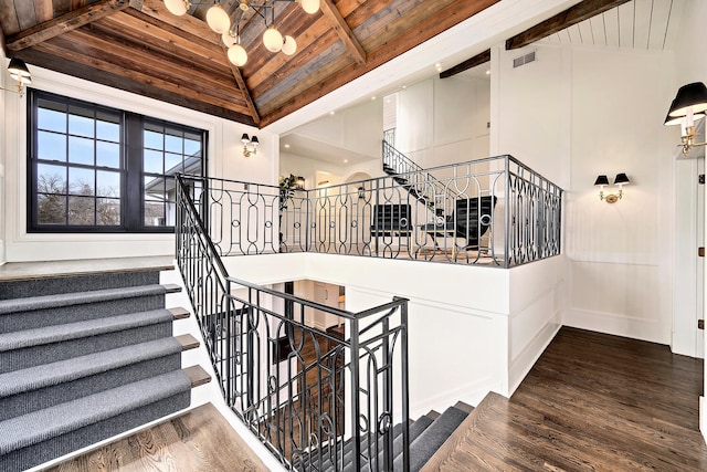 stairway featuring wood finished floors, visible vents, high vaulted ceiling, beam ceiling, and wooden ceiling