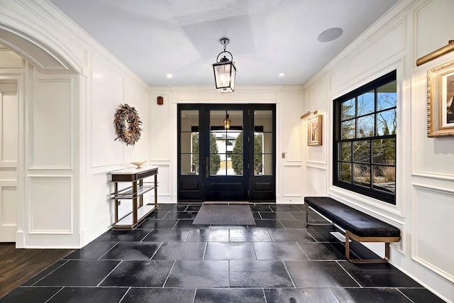 entryway with a decorative wall, recessed lighting, and ornamental molding